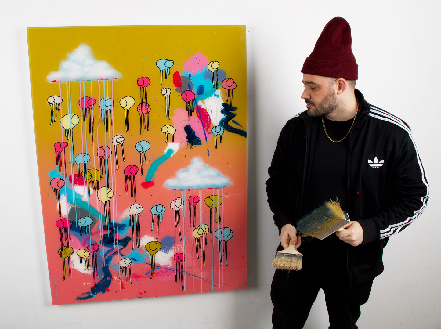 Artist Morgan Sheardown working on RAINING COWS — Bubble Gum Sun, holding a paintbrush, pink, blue and mustard yellow abstract cows, mixed media and resin on wooden panel.